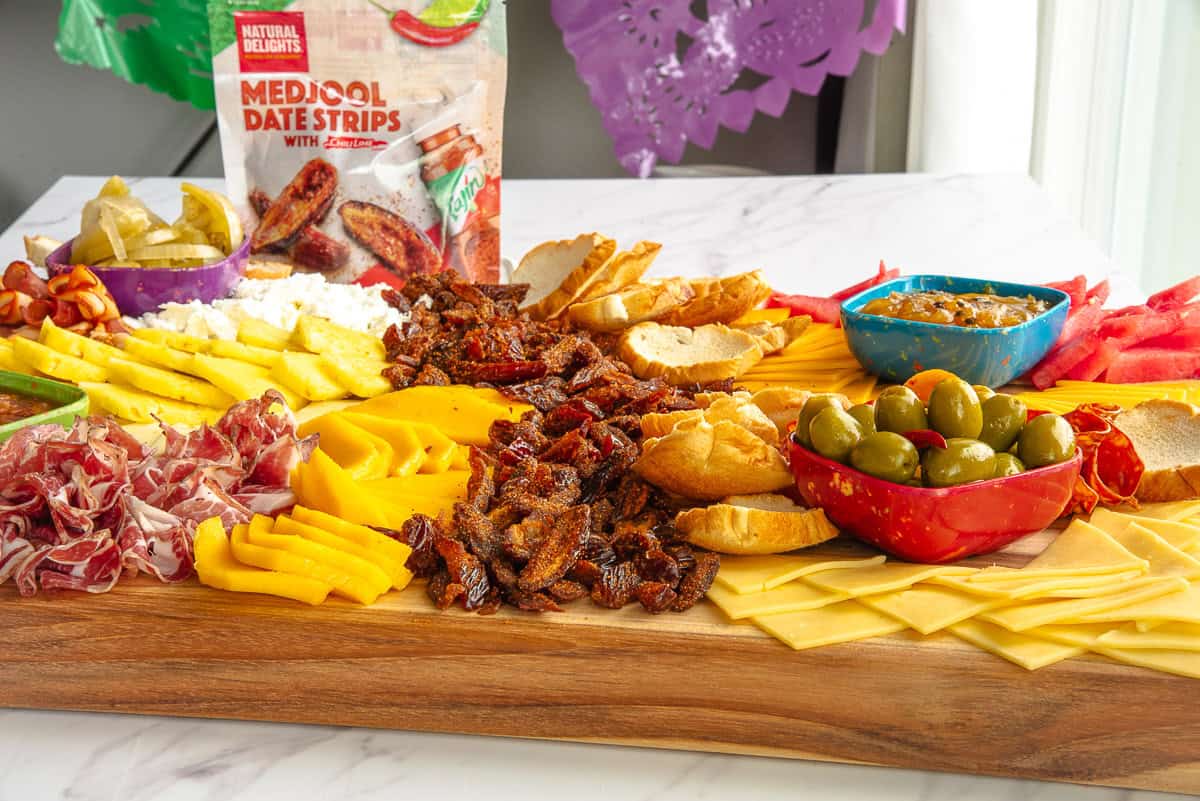 The assembled Fiesta Grazing Board in front of a bag of Medjool Date Strips.