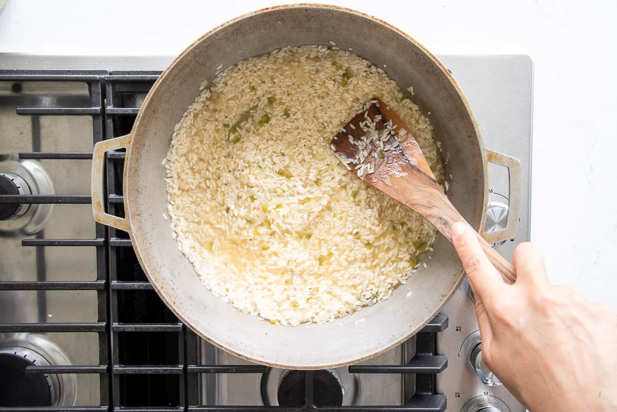 A flat wooden spoon is used to smooth out the surface of the rice prior to steaming the rice for 20 minutes.