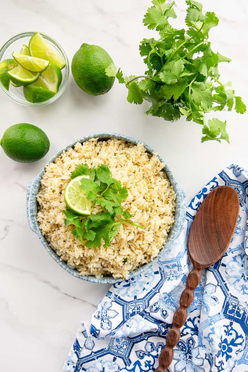 A blue and white speckled bowl of Spicy Cilantro Lime Rice garnished with a lime wedge and cilantro leaves.