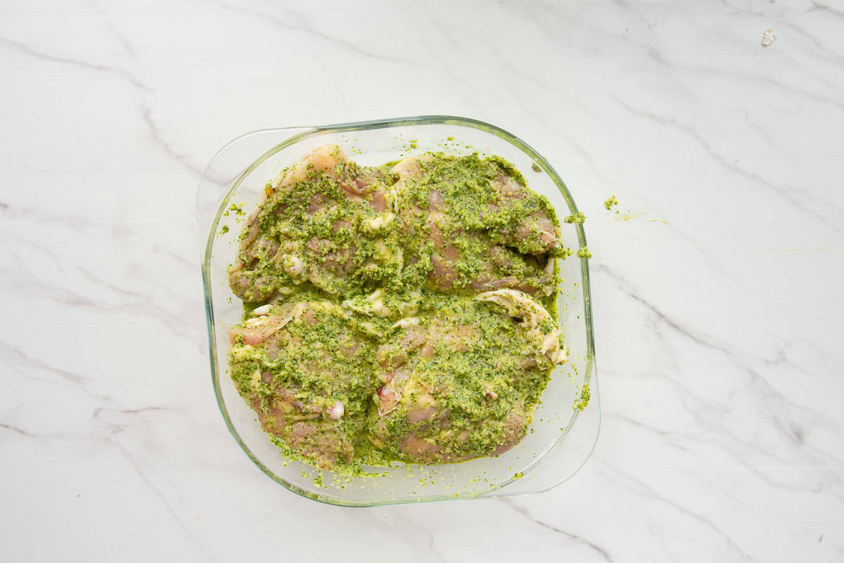 The chicken is covered in the sofrito marinade and in a shallow glass dish before being covered with plastic wrap and refrigerated.