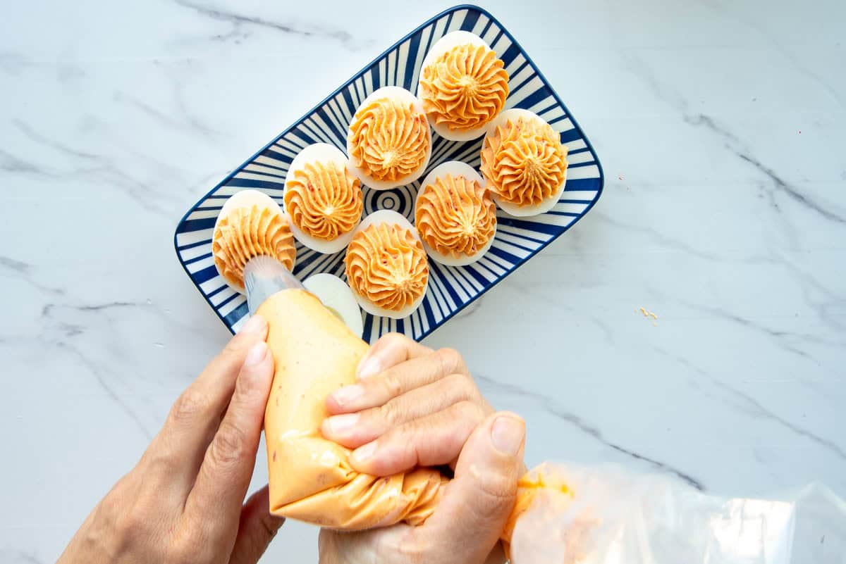 A piping bag is used to pipe the filling into the hollows of boiled egg whites.