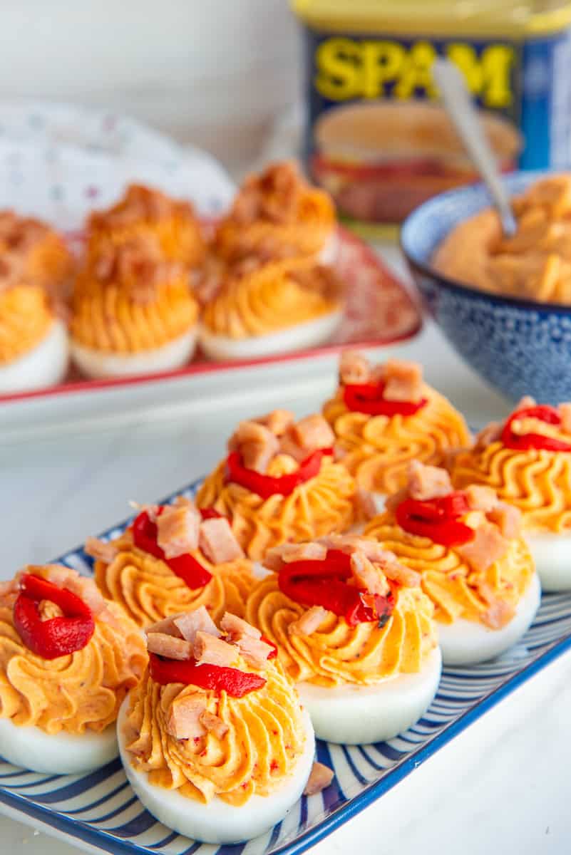 Mezcla Deviled Eggs arranged on a blue and white striped serving tray.