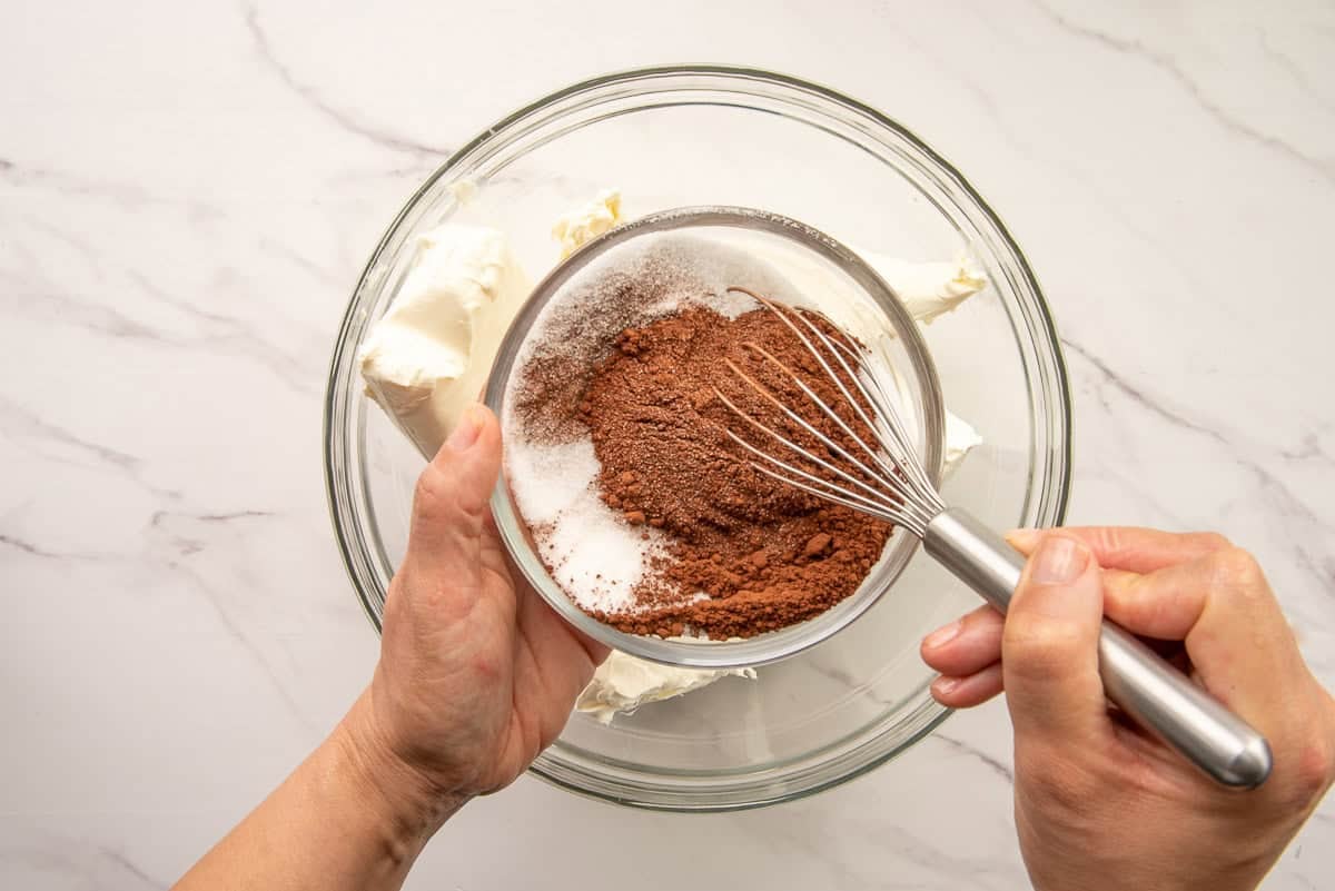 The sugar and cocoa powder are stirred together before being added to the bowl with cream cheese.