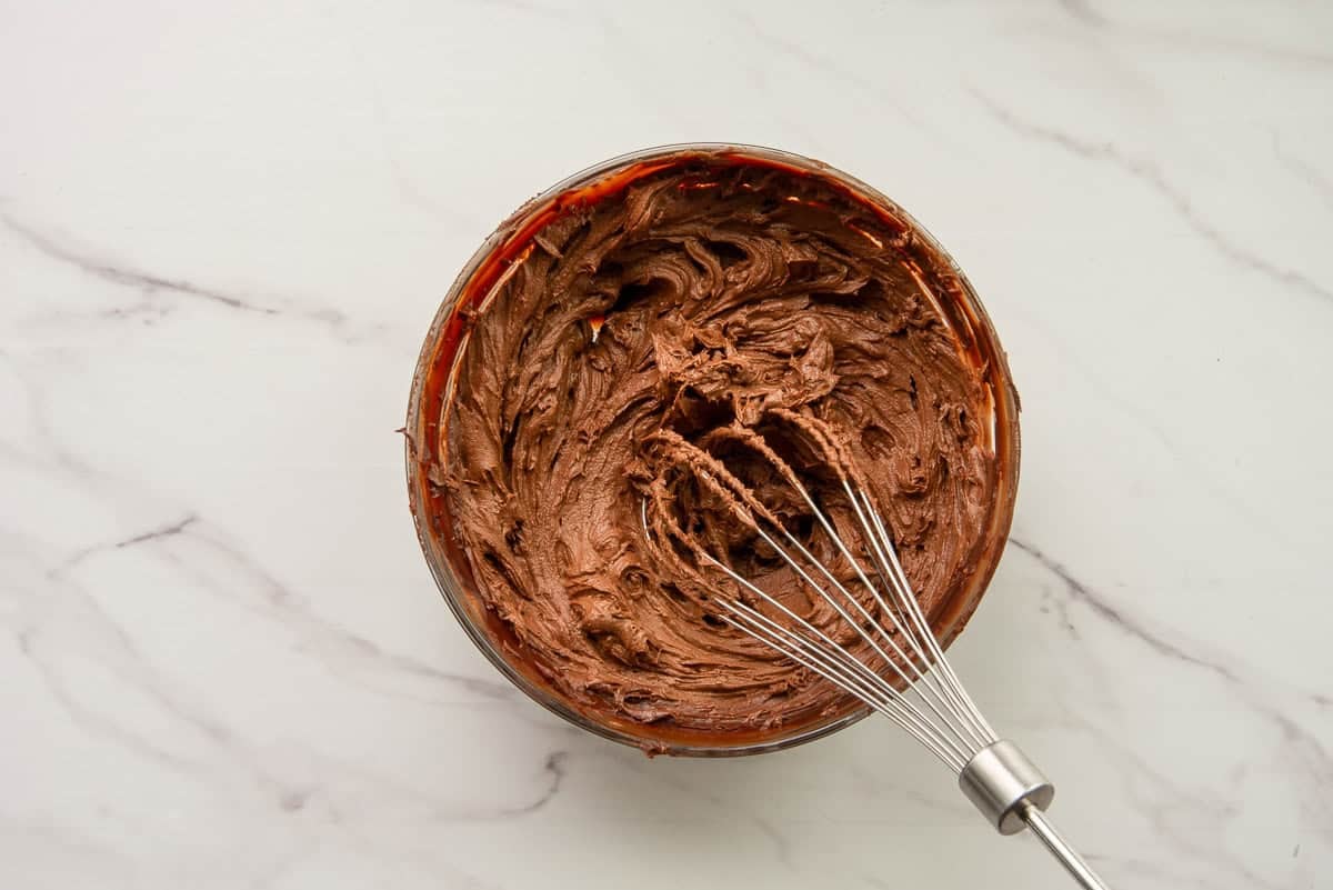 The whipped ganache in a bowl with the whisk.