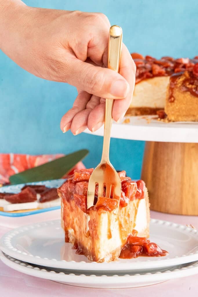 A hand uses a gold fork to remove a piece of the Cascos de Guayaba Cheesecake.