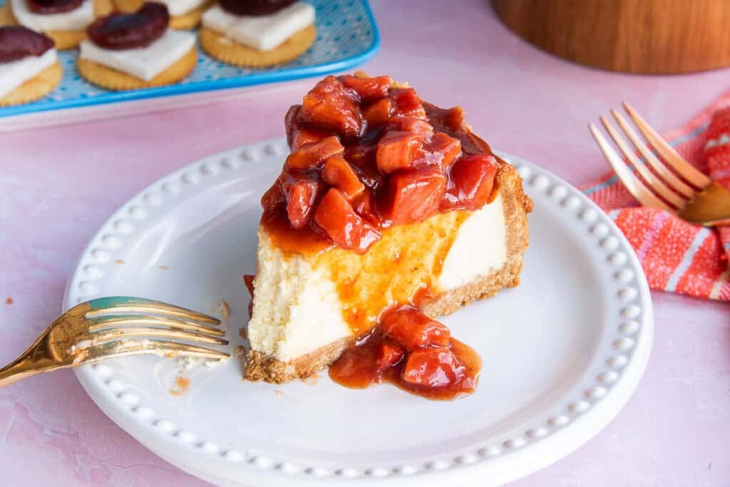 A slice of Cascos de Guayaba Cheesecake with a bite removed and a used fork propped on its plate.