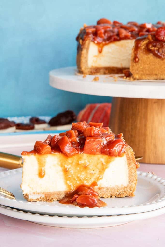 A Cascos de Guayaba Cheesecake slice on a white plate with the guava topping running down its side.