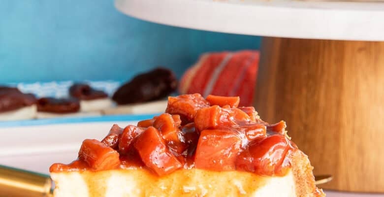 A Cascos de Guayaba Cheesecake slice on a white plate with the guava topping running down its side.
