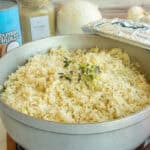 Cooked Caribbean Coconut Rice in a pot with the lid propped on its side.