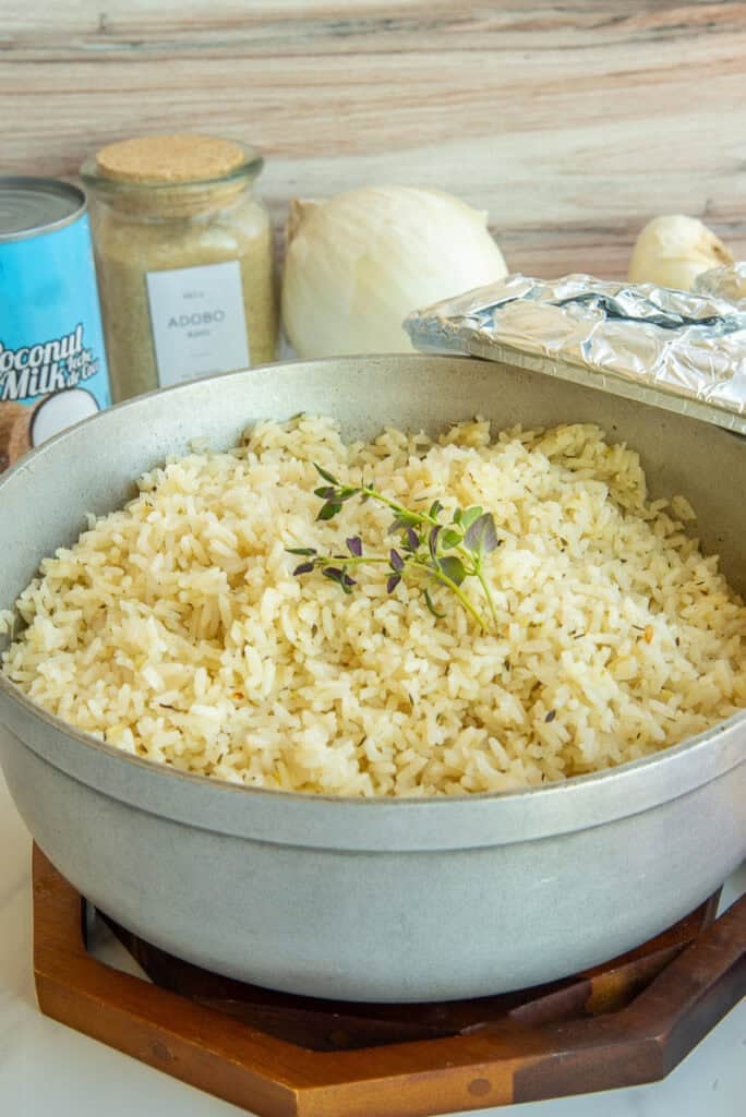 Cooked Caribbean Coconut Rice in a pot with the lid propped on its side.