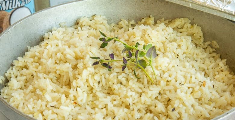 Cooked Caribbean Coconut Rice in a pot with the lid propped on its side.