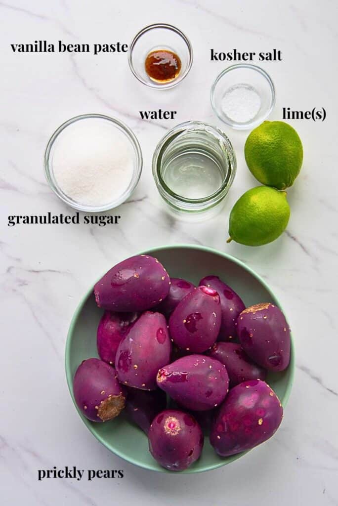 The ingredients need to make the recipe are on a white marble countertop and labeled with black text.