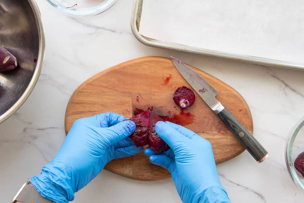 Marta's gloved hands pull the skin away from the fruit after cutting off the tough, woody ends.