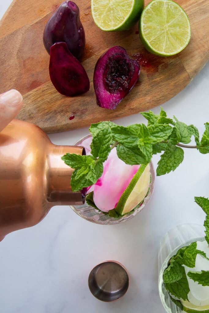 The rum mixture is poured into a highball glass that's filled with fresh mint and ice cubes.