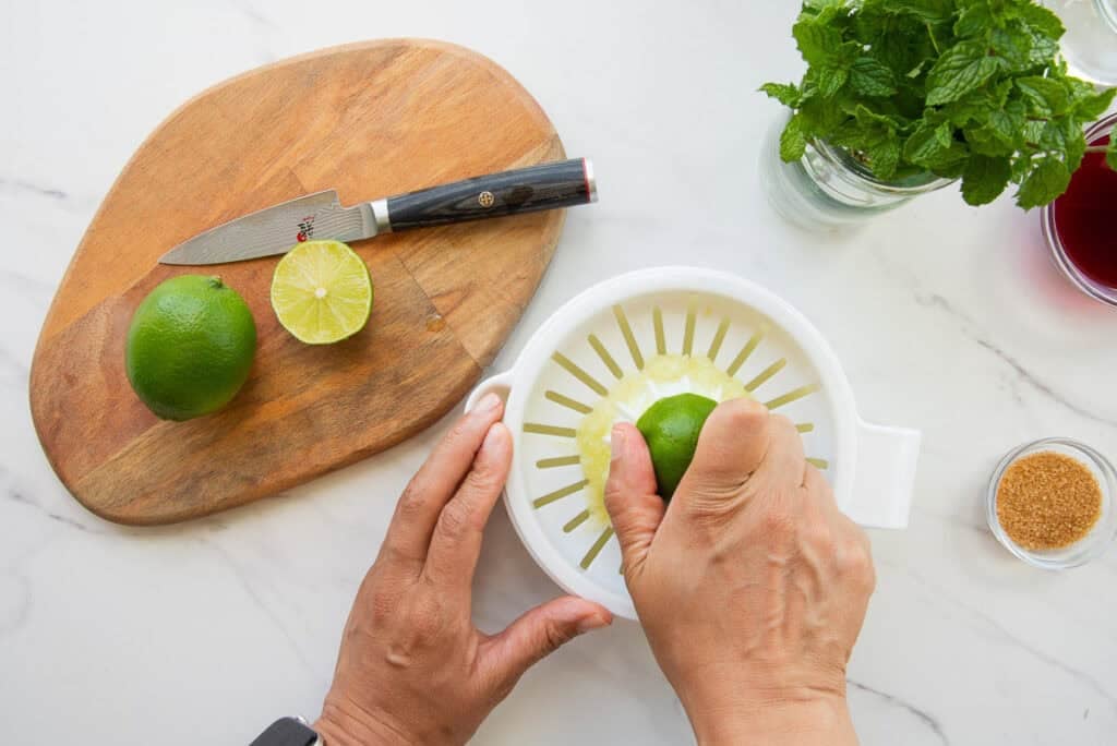 Hands juice limes to use in the recipe.