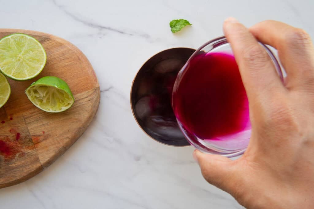 Homemade prickly pear syrup is added to the cocktail shaker with the muddled mint.
